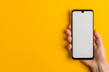 A hand holding a blank black smartphone with an empty screen on a clean background, in the paper cutout effect style, in a minimalistic style with a simple composition. Concept photography