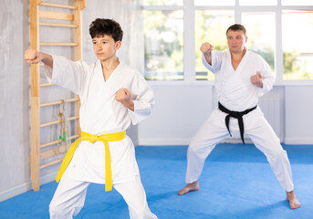 Obraz premium Karate trainer teaching block and punches to a teenager in the gym