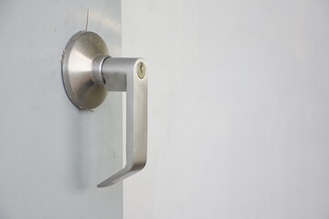 Close-up of a door handle. The door handle is made of metal and has a modern, sleek design. The handle is attached to the door and appears to be made of a smooth, light-colored material.