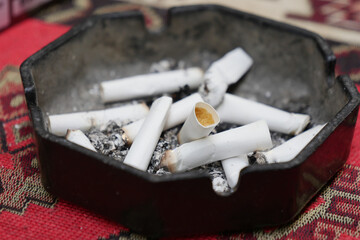 An ashtray filled with scattered cigarette butts and ashes from regular use over time