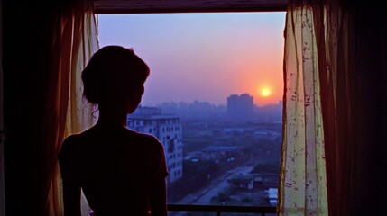 Fototapeta premium Silhouette of woman by window at sunset