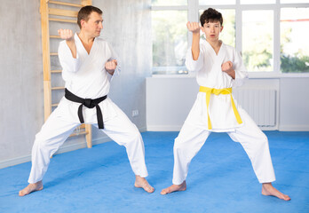 Karate trainer teaching block and punches to a teenager in the gym