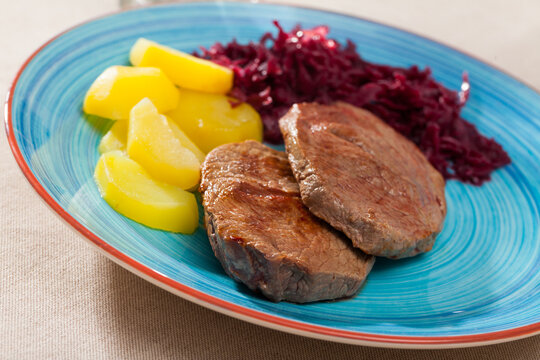 Delicious veal Medallions de cadera with boiled potato and red sauerkraut..