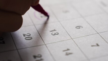 A person with a violet felt-tip pen traces the dates in the calendar. planning and marking important events and plans.