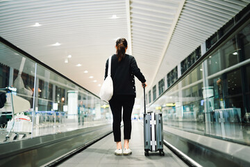 A Solo Traveler on an Airport Moving Walkway at Night