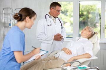 Fototapeta premium Skilled male beautician giving consultation to woman patient with mirror in aesthetic clinic