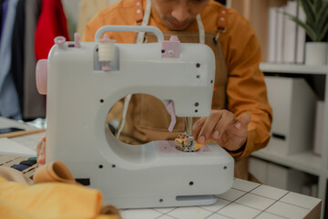 a fashion designer is working in his studio doing what he loves, he does many things such as using a sewing machine to sew a dress, choosing the fabric to use to make the dress