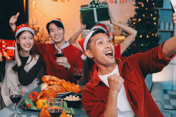 Group of young Asian man and women as friends having fun at a New Year's celebration, holding gift...