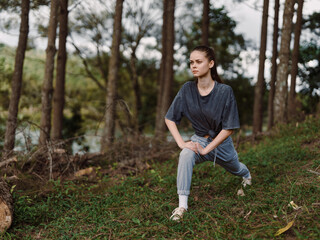 Focused young woman stretching in a forest, preparing for outdoor workout Fitness and wellness concept with natural background enhancing tranquility