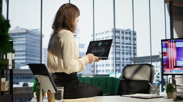 Woman CEO reviewing sales reports and market trends from analytics files, using data driven insights to adjust strategies and maximize business growth opportunities. Strategic thinking. Camera B.