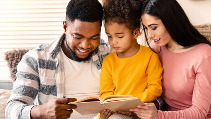 Happy international family reading book together at home during covid-19 quarantine