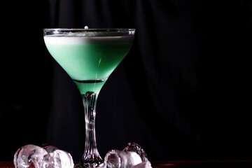 Close-up of a bartender's hands mixing a blue-colored cocktail in a long-stemmed glass tumbler