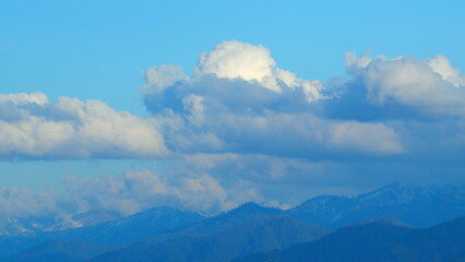 Blue Sky And White Clouds. Snow-Covered Mountain Peaks Against A Blue Sky With Clouds.