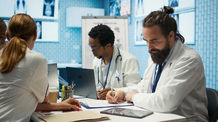 Obraz premium Physician writing a prescription for treatment plan at his cabinet desk, recommending medicine for disease prevention. Medic consulting analytics and hospital records in a clinic. Camera B.