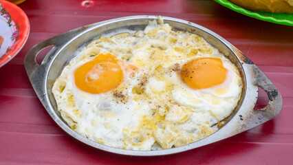 Sunny-side up egg on a frying pan. Delicious fried egg, Banh mi chao. Fried eggs in a frying pan. Vietnam street food.