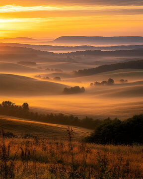 A stunning sunrise over rolling hills and a misty valley, bathed in the warm glow of the golden hour.