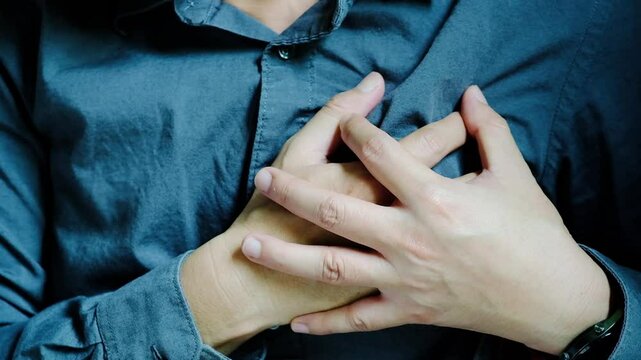 Man is sick and in pain and uses his hands to squeeze his chest He had chest pain caused by an acute heart attack. medical and health concepts