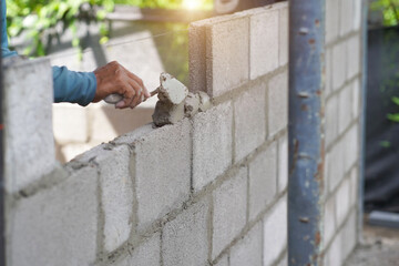 masonry worker make concrete wall by cement block and plaster at construction site