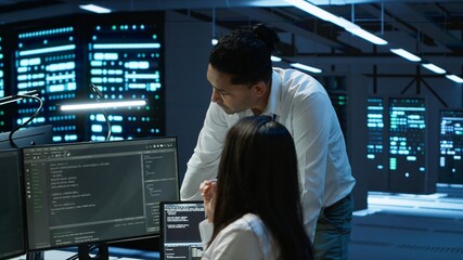 Engineering team colleagues in data center managing gear energy consumption, working on PC....