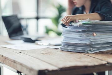 Overwhelmed: A close-up shot of a person struggling with a large stack of paperwork on a rustic...
