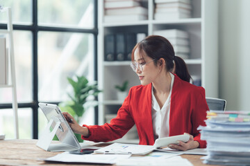 Focused Determination: A young businesswoman in a red blazer exudes concentration as she...