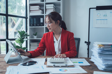 Focused and Determined:  A dedicated businesswoman sits at her desk, meticulously reviewing...