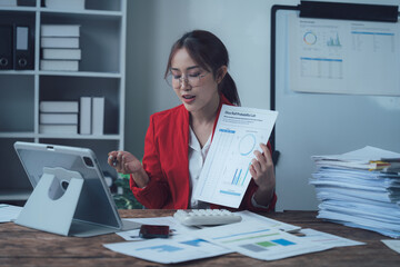 Focused on the Data: An ambitious businesswoman meticulously analyzes financial reports on her...
