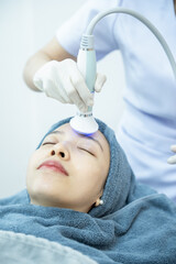Naklejka premium Beautician hand making ultrasound facial procedure by special equipment.