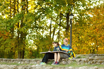 two young and innovative female artists conducting an outdoor painting lesson. Surrounded by...