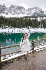 Woman in Karersee lake with snow in the Dolomites, Italy.