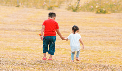 Older brother is holding hand with her sister. They look so happy together.