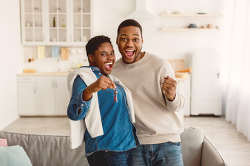 Moving Day. Happy African American couple holding and showing keys of their new apartment house,...