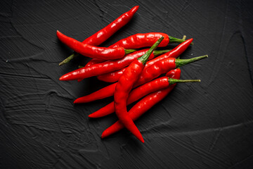 A pile of red, hot chili peppers on a black background. View from above. Space for text Close-up.