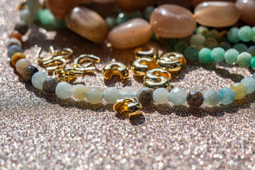 Close up photo featuring a collection of beads made from natural stones, gold-plated beads, and tools for crafting jewelry. Image for jewelry designers, crafters, for web banners.