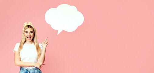 Comment. Happy young blonde woman standing isolated over pink wall pointing up at speech bubble with copyspace