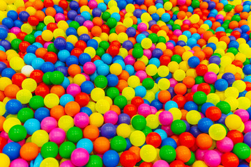 Brightly colored plastic balls in multiple hues fill a lively play area, creating a fun environment for children to enjoy during a sunny outing.