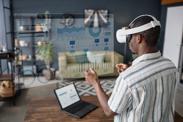 Young Black freelancer wearing VR headset standing in living room surfing Internet