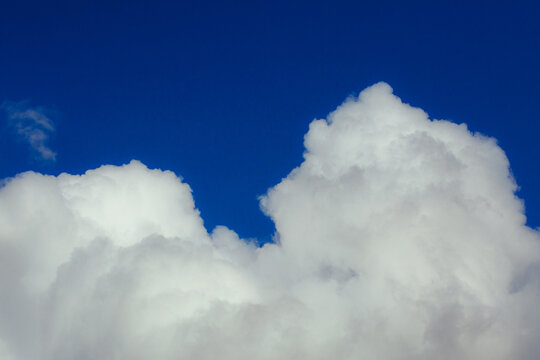 Cumulus clouds. Beautiful dark blue dramatic sky. Copy space for lettering. Few clouds against a blue sky on a sunny day.