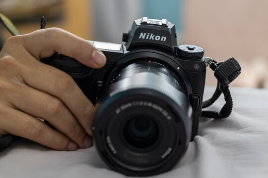 Close-up Man hand holding a mirrorless camera Brand Nikon