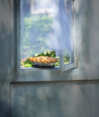Fresh baked warm home made apple pie cooling after being cooked and sitting on the window sill. Classic American domestic scene. © Brocreative