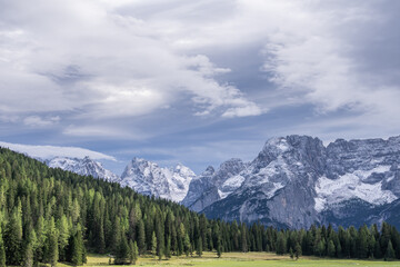 Obraz premium Mountains landscape in winter summits and rocky tower peaks above green valley alpine Dolomites, Italy.