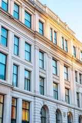 Fototapeta premium Elegant historic building exterior with large windows reflecting sunlight in an urban setting