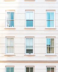 Fototapeta premium Modern building facade with multiple windows reflecting sunlight in an urban setting