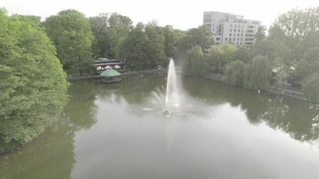 Circle above pond with fountain and surrounding trees 4k drone footage Dlog 10 Bit ungraded