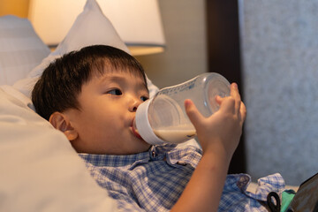 Asian Chinese baby boy age 3 to 4 drinking milk with holding milk bottle by him self.