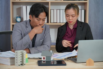 A real estate sales representative talks to explain real estate investment documents along with a home sales contract and home insurance to clients.