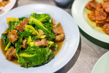 Stir fried baby cabbage with crispy pork on dish