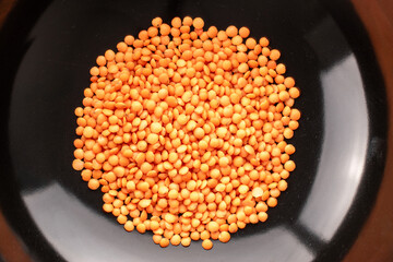 Raw red lentils in a ceramic dish , macro, top view.