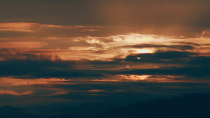 Obraz premium Sun Rises Over A Mountain Range Under Dramatic And Swirling Clouds. Dramatic Sky.