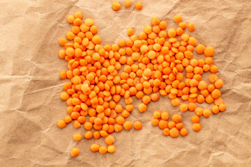 Raw red lentils  on kraft paper, macro, top view.